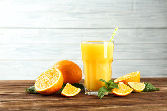 Composition with glass of fresh juice and oranges on wooden table