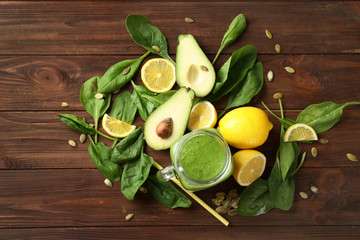 Composition with mason jar of spinach smoothie on wooden background