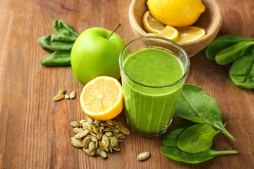 Glass of spinach smoothie on wooden background