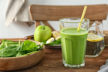 Glass of spinach smoothie on wooden table