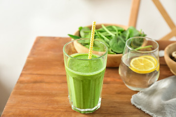 Glass of spinach smoothie on wooden table