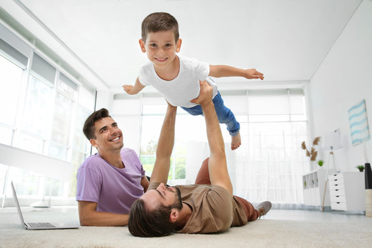 Male Gay Couple Playing With Foster Son. Adoption Concept
