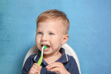 Adorable little boy brushing teeth on color background