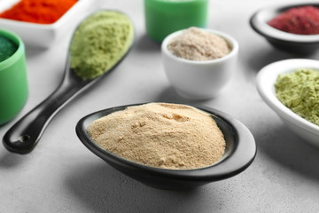Various colorful superfood powders in kitchenware on grey background