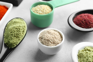 Various colorful superfood powders in kitchenware on grey background