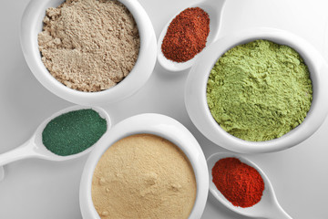 Various colorful superfood powders in kitchenware on light background
