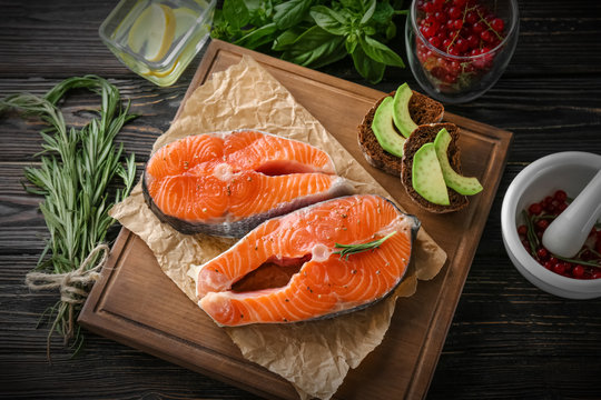 Fresh salmon steaks with rosemary on wooden board