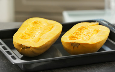 Halves of fresh spaghetti squash on baking sheet