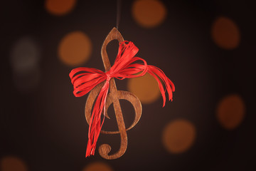 Christmas music concept. Decorative clef with bow on blurred background