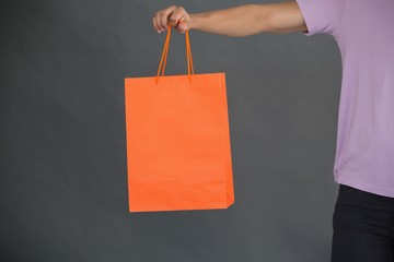 Man holding shopping bag against grey background