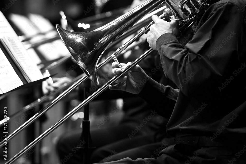 Poster Trombones in the hands of the musicians in the orchestra in black and white 