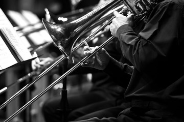 Trombones in the hands of the musicians in the orchestra in black and white 