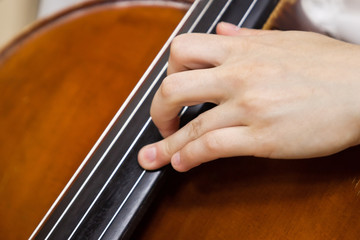 The hand of the musician on the strings of a cello closeup