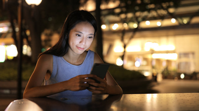 Woman use of samrt phone in city at night