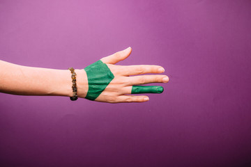 one woman hand, Caucasian painted green hand skin, purple magenta background, jewelery bracelet
