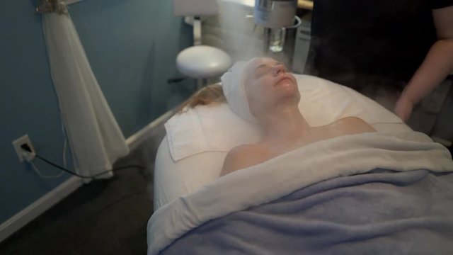 Massage receives a steam treatment on her face during her facial. Steadicam shot.