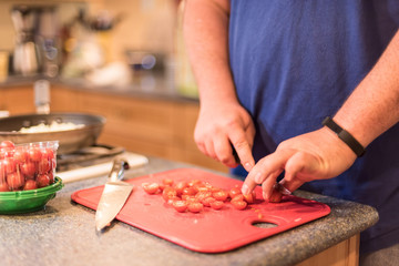 Man chopping tomatoes and preparing a healthy meal - soft focus