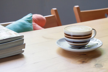 Cappuccino on wood table, book, magazine