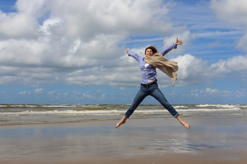 Happy young woman jumping on background of the sea.