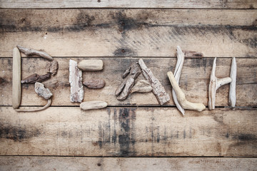 Beach sign made of driftwood on a wooden background