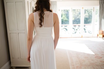 Bride in wedding gown standing at home