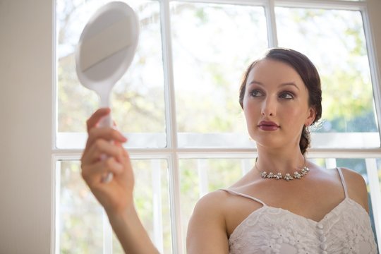 Beautiful Bride Looking Into Hand Mirror While Standing By