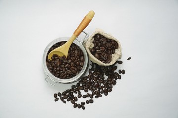 Coffee beans inside the sack bag and a jar on white isolated background.