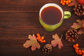 Autumn concept, fallen red-yellow leaves with apples, pine cones and a cup of tea on a wooden table. Thanksgiving Day.