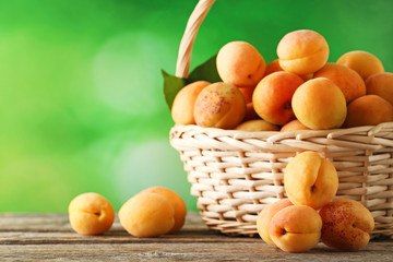Sweet apricots in basket on grey wooden table