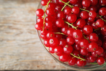 Red currants in glass bowl on grey wooden table