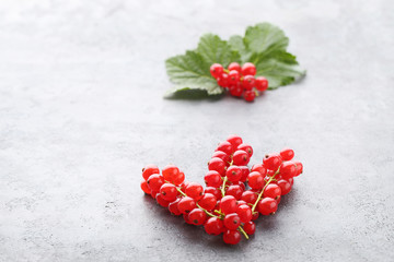 Red currants with leafs on grey wooden table