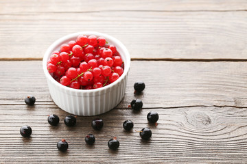Red currants in bowl on grey wooden table