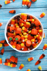 Halloween candy corns in bowl on blue wooden background