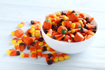 Halloween candy corns in bowl on blue wooden background
