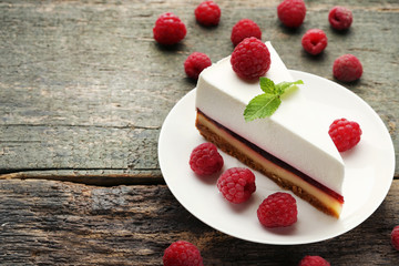 Tasty raspberry cheesecake in plate on wooden table