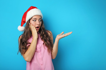 Portrait of young woman in santa hat on blue background