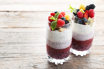 Chia pudding with berries in glasses on grey wooden table