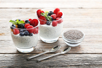 Chia pudding with berries in glasses on grey wooden table