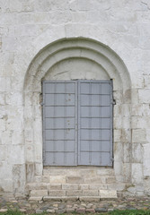 Vintage steel door. Gate of castle. Gray iron door on white wall