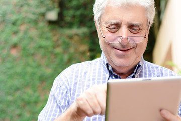 Obraz premium Old man using digital tablet.