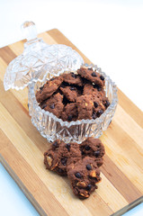 Delicious almond chocolate chips cookie in a glass container on a wooden board on white background
