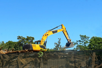 Excavator working at the demolition of an old house, yellow machine, construction site, demolition of debris, sunny day 