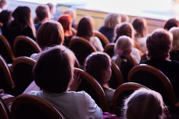 The audience in the theater watching a play. The audience in the hall: adults and children.