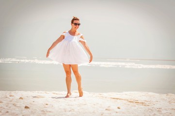 Young attractive Caucasian girl dancing barefoot on a salty island in the Dead Sea.