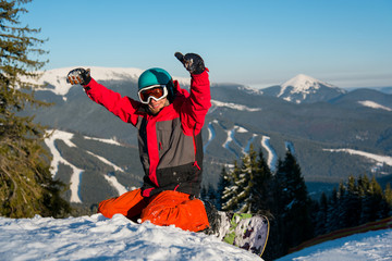 Shot of a cheerful snowboarder smiling showing thumbs up resting after riding the slope activity...