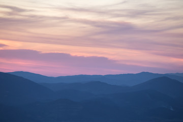 Fototapeta na wymiar Layers of mountains and hills at sunset, with warm and soft tones