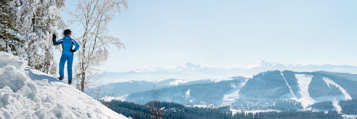 Panoramic shot of a female skier resting on top of the mountain observing nature at ski resort on a beautiful sunny winter day copyspace peaceful recreational vacation travel concept