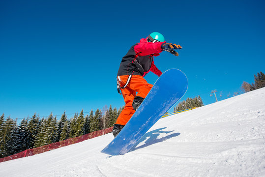 Snowboarder jumping in the air while riding on the slope at winter ski resort in the mountains active lifestyle winter sports concept