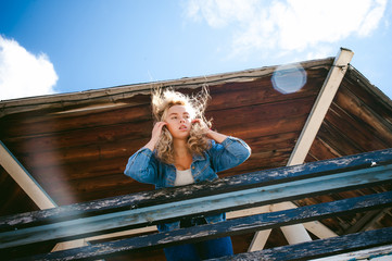 young beautiful woman in jeans clothes outdoors. portrait of a girl with freckles on her face, stylish girl on sea beach rescue tower, on a sunny summer autumn day.