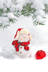 christmas decoration a little snowman under a spruce branch in the snow. Christmas concept